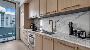 Een moderne keuken met houten kastjes, een marmeren aanrecht, een spoelbak, een fornuis en een broodrooster.