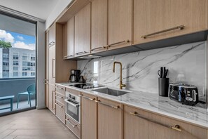 A modern kitchen with wooden cabinets, a marble countertop, a sink, a stove, and a toaster. - 2 Units on One Floor for 8 · Wynwood Rooftop Pool (Miami)