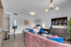 A modern living room with a sofa, a dining table, and a cityscape painting. - 2 Units on One Floor for 8 · Wynwood Rooftop Pool (Miami)