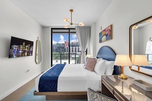 Een hotelkamer met een groot bed, uitzicht op de stad, een moderne kroonluchter en een grote spiegel.