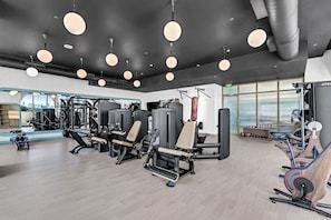 A gym with various exercise equipment, large windows, and a modern design. - Wynwood 2-Unit Combo for 8 · Same Floor + Rooftop (Miami)