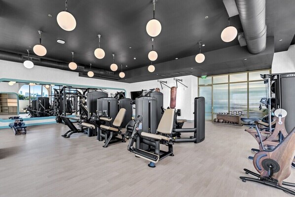 A gym with various exercise equipment, large windows, and a modern design. - Wynwood 2-Unit Combo for 8 · Same Floor + Rooftop (Miami)