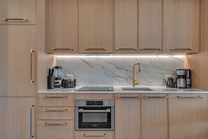 A modern kitchen with wooden cabinets, a Bosch oven, a coffee maker, and a marble countertop. - Wynwood 2-Unit Combo for 8 · Same Floor + Rooftop (Miami)