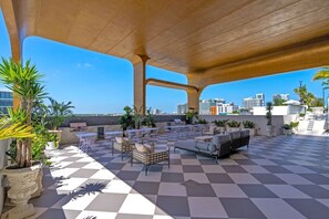 An outdoor patio area with checkered flooring, seating arrangements, and potted plants. - Wynwood 2-Unit Combo for 8 · Same Floor + Rooftop (Miami)