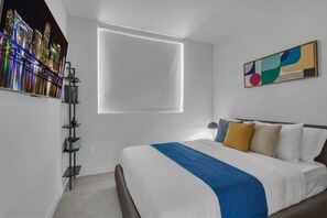 A modern hotel room with a large bed, a cityscape view, a minimalist decor, and a unique wall art piece. - 2 Apts for 8 · 2BR/2BA, Rooftop Pool, Downtown MIA (Miami)