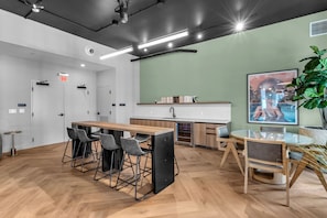 A modern kitchen with a wooden table, bar stools, and a glass-top dining table. - 2 Apts for 8 · 2BR/2BA, Rooftop Pool, Downtown MIA (Miami)