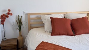 Ein Schlafzimmer mit einem Bett, Kissen, einem Nachttisch mit einer Vase und Wandkunst.