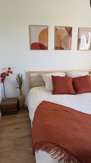 A bedroom with a bed, pillows, a bedside table with a vase, and wall art. - A peaceful retreat with a pool and a view of the countryside (Preignan)