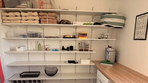 Ein Waschraum mit Waschmaschine, Trockner, Regalen und Aufbewahrungsbehältern sowie einer Kaffeemaschine.