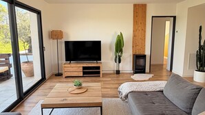 Ein modernes Wohnzimmer mit einem großen grauen Sofa, einem Flachbildfernseher, einem Couchtisch aus Holz und einem Topf mit Pflanze.