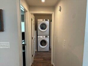 A laundry room with two stacked washing machines and a door leading to another room. - Cute & Updated Home with Country Charm (Bloomington)