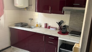 A kitchen with a sink, cabinets, a water heater, and a microwave.