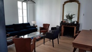 A living room with a sofa, chairs, a coffee table, a fireplace, and a large mirror.