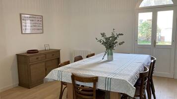 A dining area with a table set for four, a vase with flowers, and a wooden cabinet.