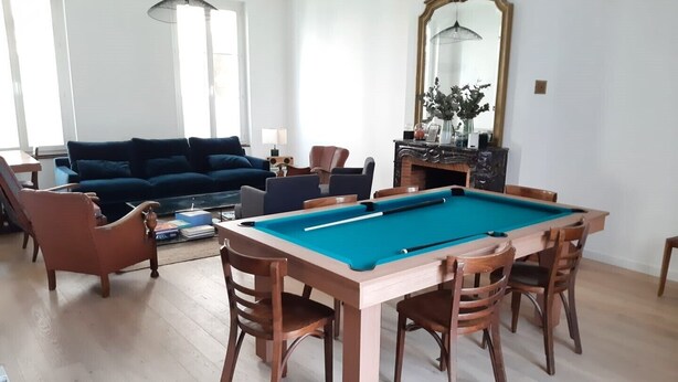 A room with a pool table, a sofa, and a dining table with chairs.