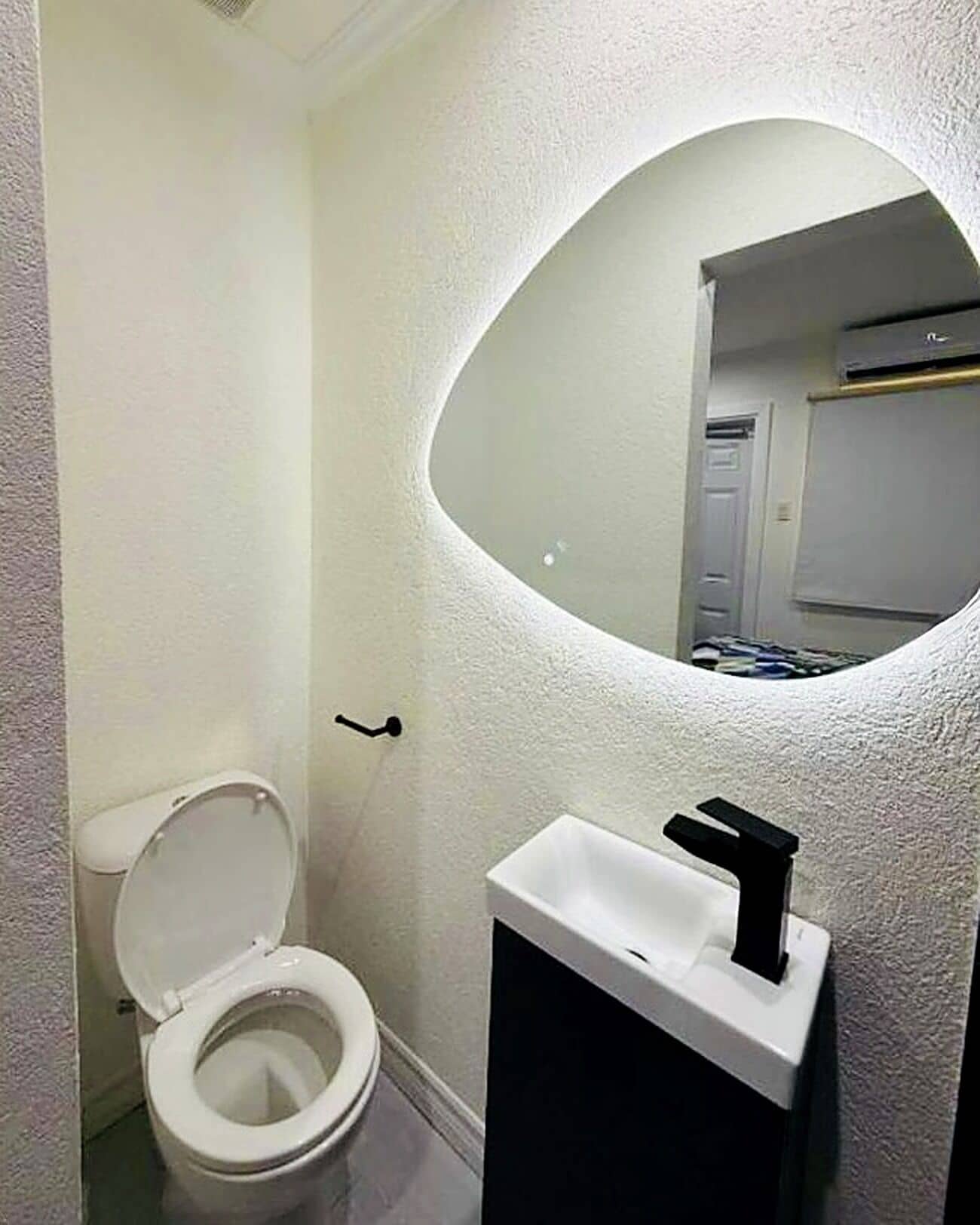 Baño con inodoro, lavamanos y espejo.