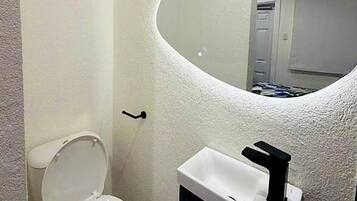 Baño con inodoro, lavamanos y espejo.