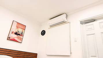 Un dormitorio con cama, aire acondicionado, un reloj y una puerta.