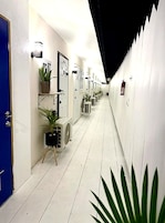 A corridor with white walls, doors, and potted plants.