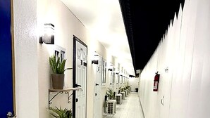 Un pasillo con paredes blancas, puertas y plantas en macetas.