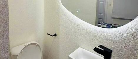 A bathroom with a toilet, a sink, and a mirror.