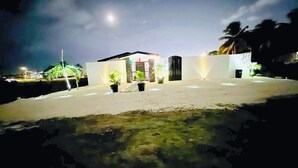 Un edificio moderno con techo plano, plantas en macetas y una entrada bien iluminada.