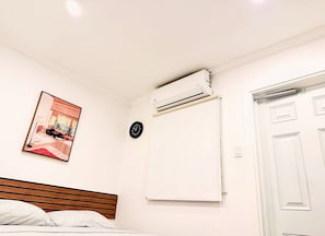 Un dormitorio con cama, aire acondicionado, un reloj y una puerta.