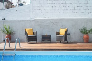 A poolside area with two wicker chairs and a small table, a ladder leading into the pool, and potted plants. - Memories - Local Lodging (Nogueira da Regedoura)