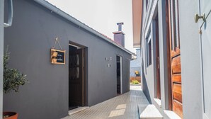 Un estrecho callejón con un edificio gris a un lado y una puerta de madera al otro.