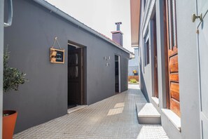 A narrow alleyway with a grey building on one side and a wooden door on the other. - Memories - Local Lodging (Nogueira da Regedoura)