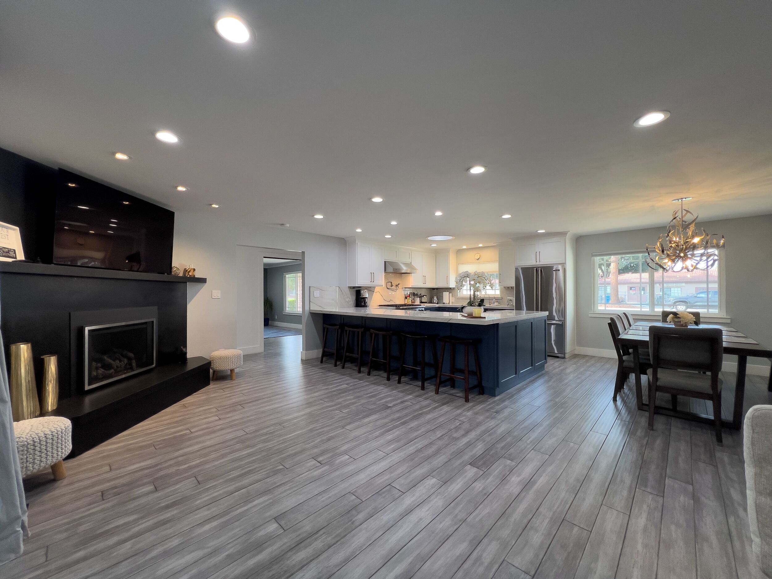 A modern kitchen with a central island, built-in appliances, and a dining area with a chandelier.