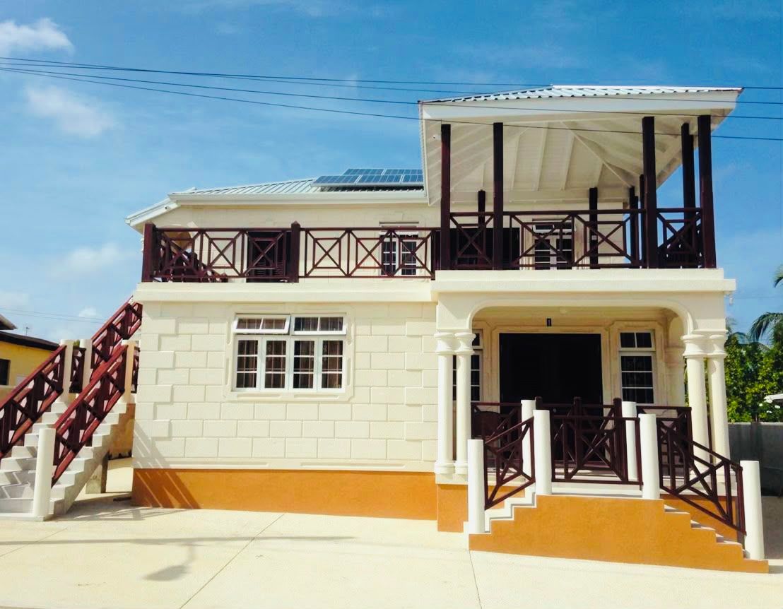 A two-story building with a balcony, a staircase, and a covered entrance.