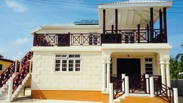 A two-story building with a balcony, a staircase, and a covered entrance.