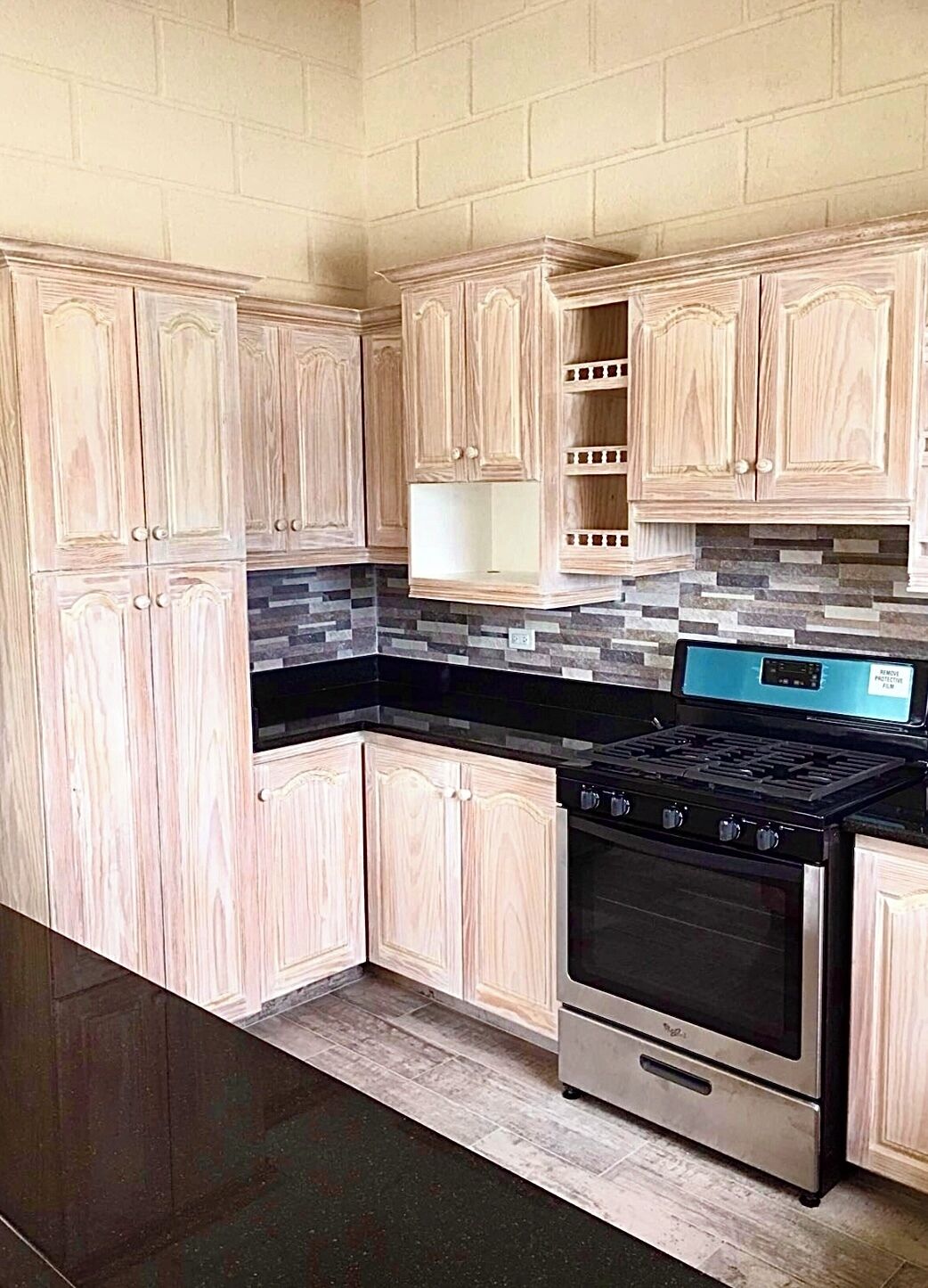 A kitchen with wooden cabinets, a black countertop, and a stainless steel stove.