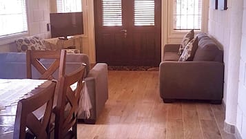 Una sala de estar con un sofá, una mesa de comedor con sillas y un televisor.