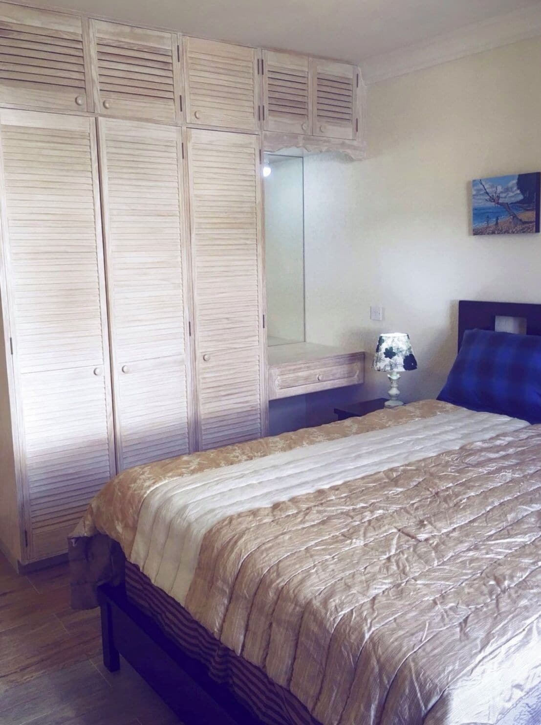 Un dormitorio con cama, mesita de noche, lámpara y armario.