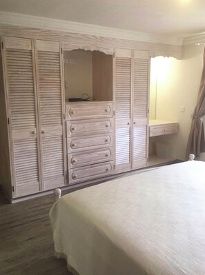 Ein Schlafzimmer mit einem Bett, einem Schminktisch und einem Kleiderschrank mit viel Stauraum.