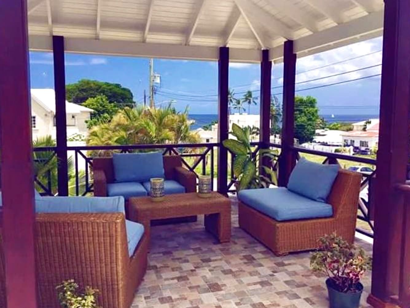 A covered outdoor seating area with wicker furniture and a tiled floor.