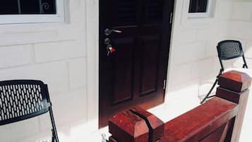 Un banco de madera frente a un edificio con una puerta negra y dos ventanas.