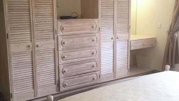A bedroom with a bed, a dresser, and a wardrobe with multiple compartments.