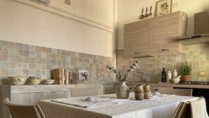A kitchen with a dining table, chairs, and various kitchen items.