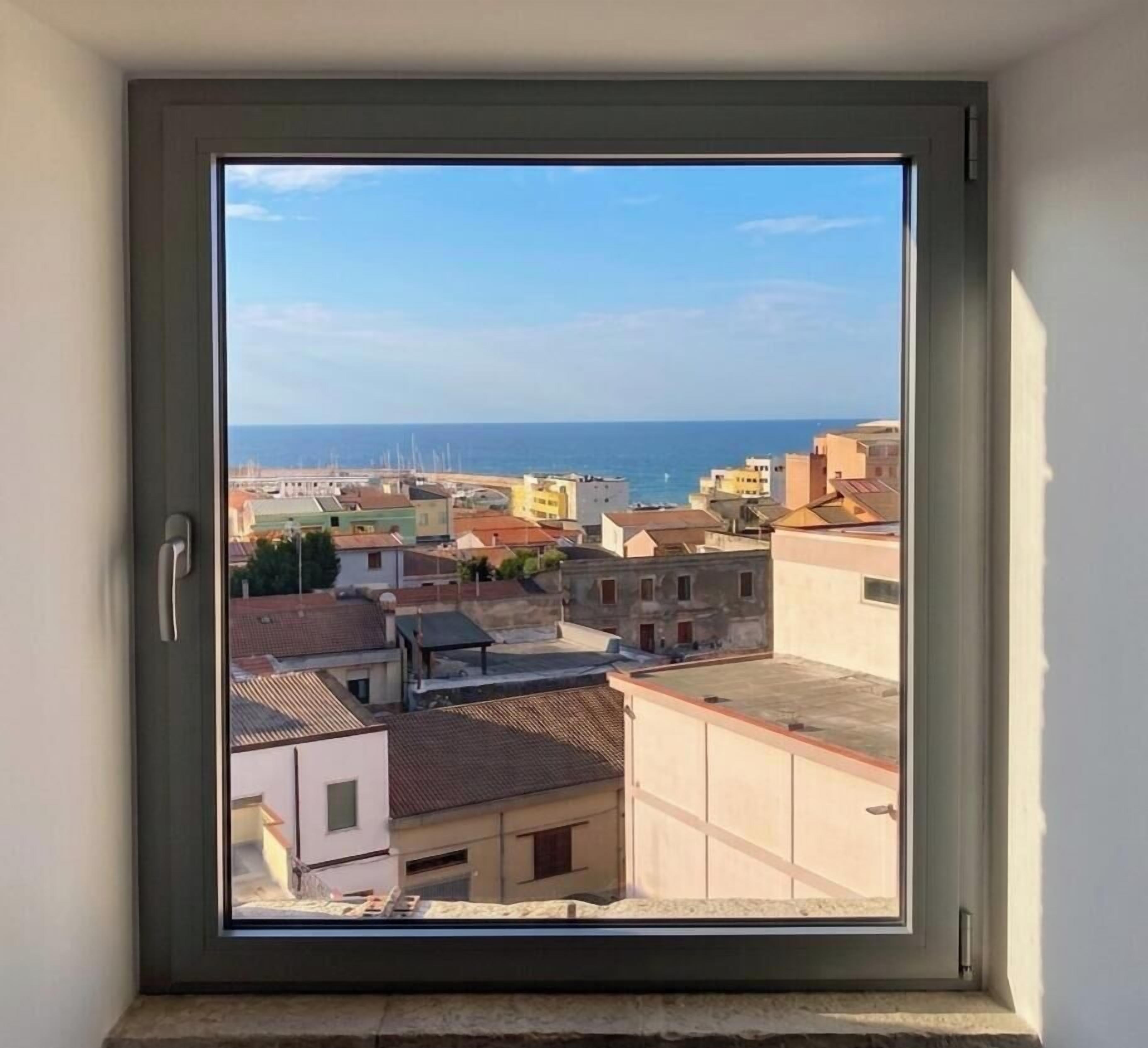 Una ventana con vista a una ciudad costera, que incluye edificios y el mar.