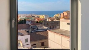 A window with a view of a coastal cityscape, including buildings and the sea.