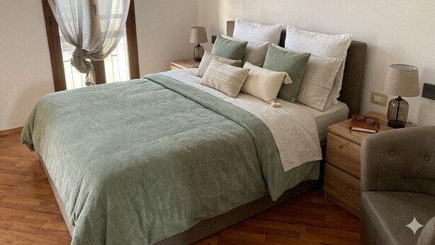 A bedroom with a bed, nightstands, and a chair.