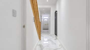 A hallway with a marble floor, a wooden staircase, and a radiator.