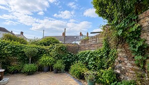 A courtyard with stone walls, potted plants, and a clear sky. - Cardiff 5-bed House, Sleeps 13 w/ Parking & Garden (Cardiff)