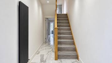 A modern interior with a marble floor, a wooden staircase, and a radiator.