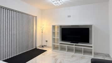 A modern living room with a flat-screen TV, a radiator, a floor lamp, and a marble floor.