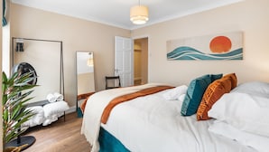 Ein Hotelzimmer mit Bett, Spiegel, Tür, Wandbild und Topfpflanze.