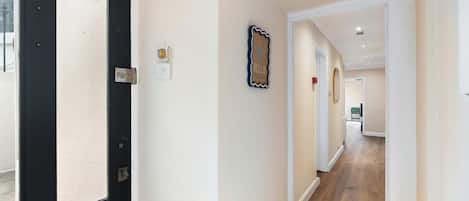 A hallway with a black door, a wall-mounted light switch, and a decorative starfish sign.